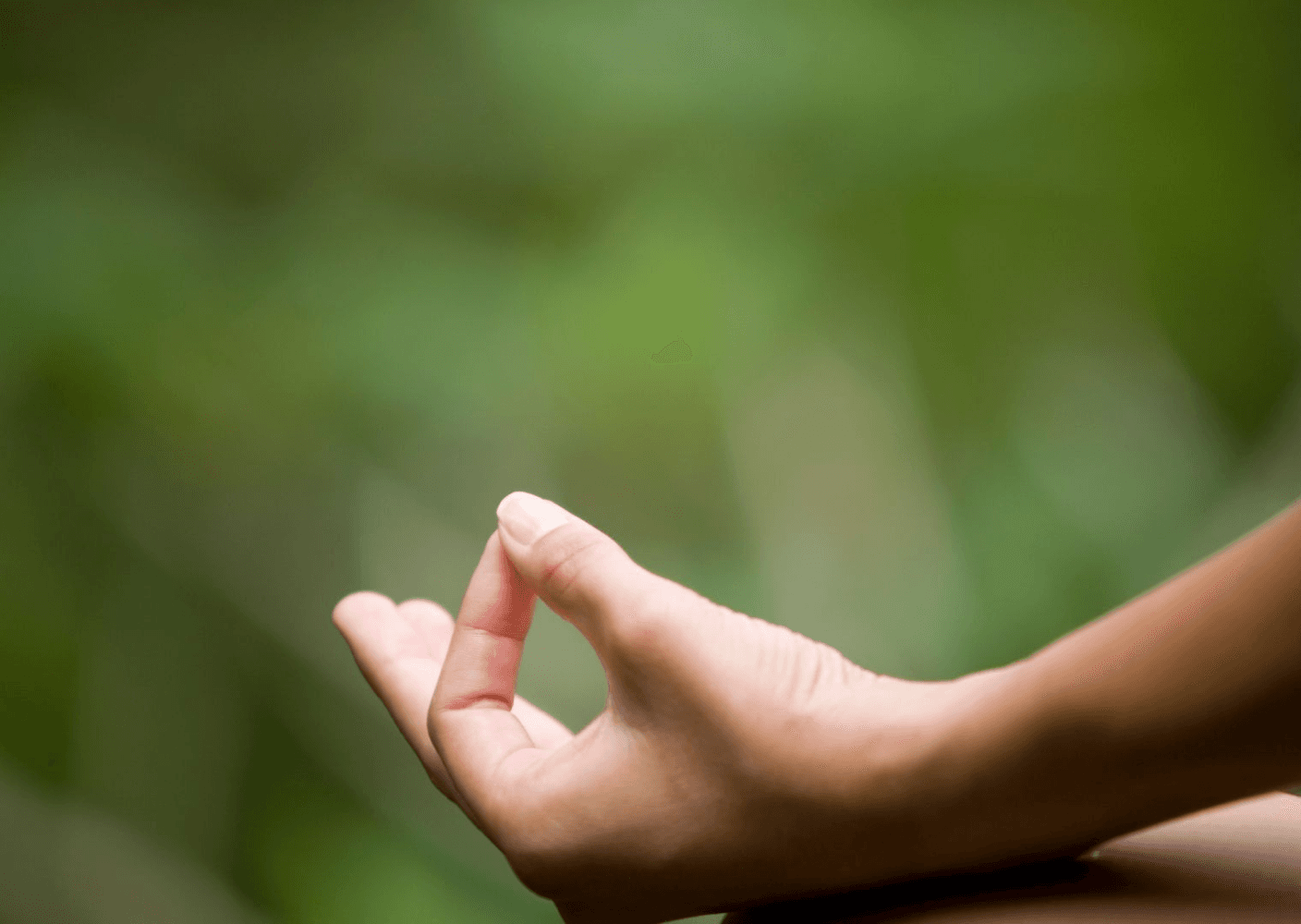 Close-up photo of a hand in a meditation pose against a blurred green background.