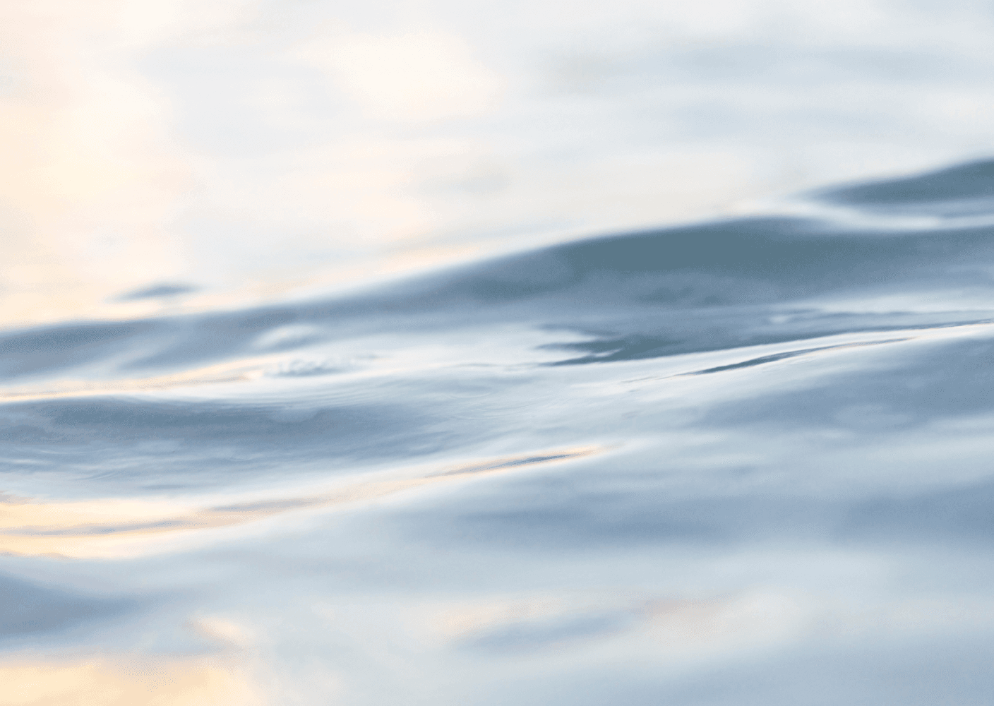 Close-up photo of calm water surface with soft light reflections.