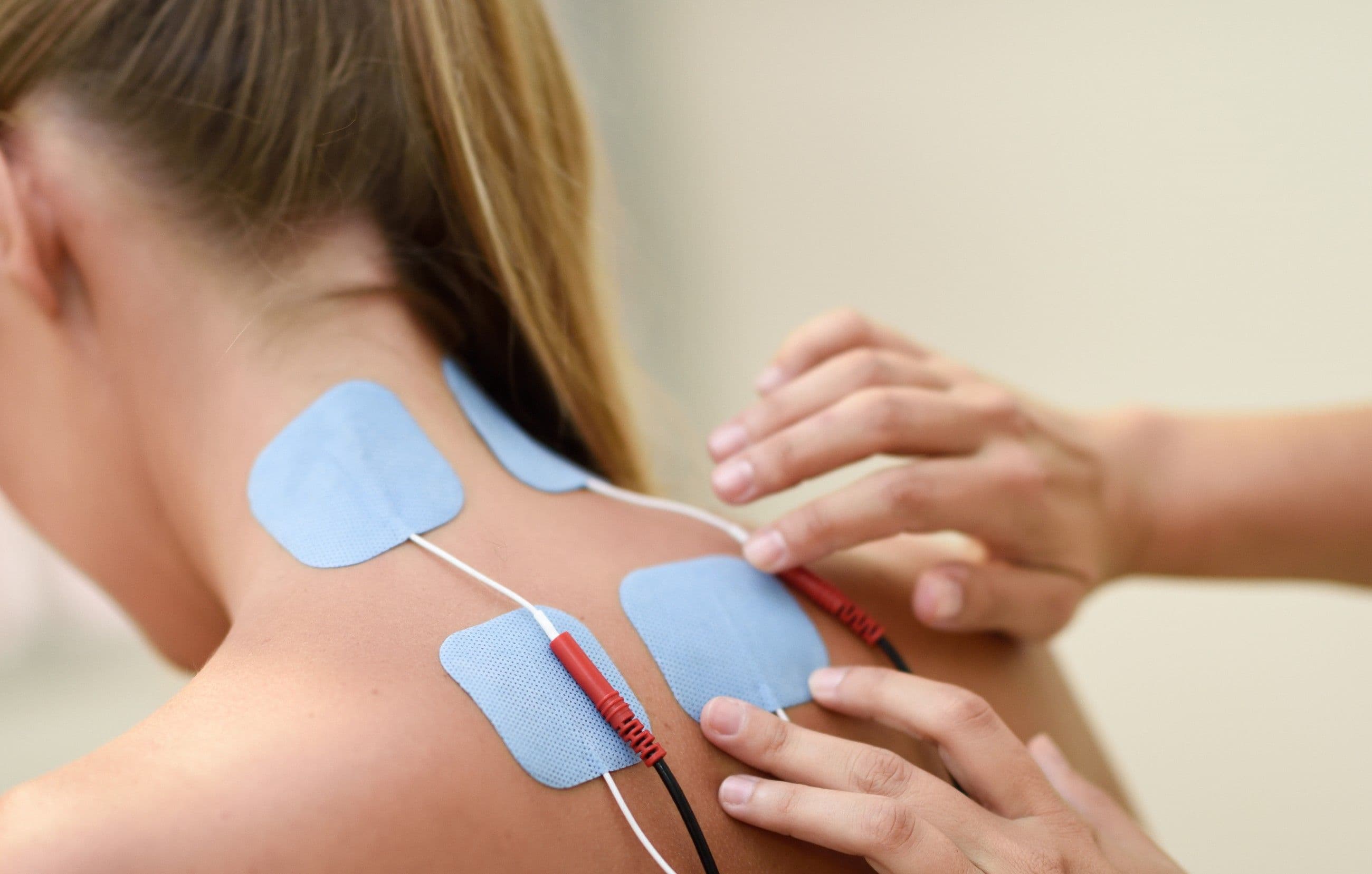 TENS electrode pads placed on a person's upper back and neck