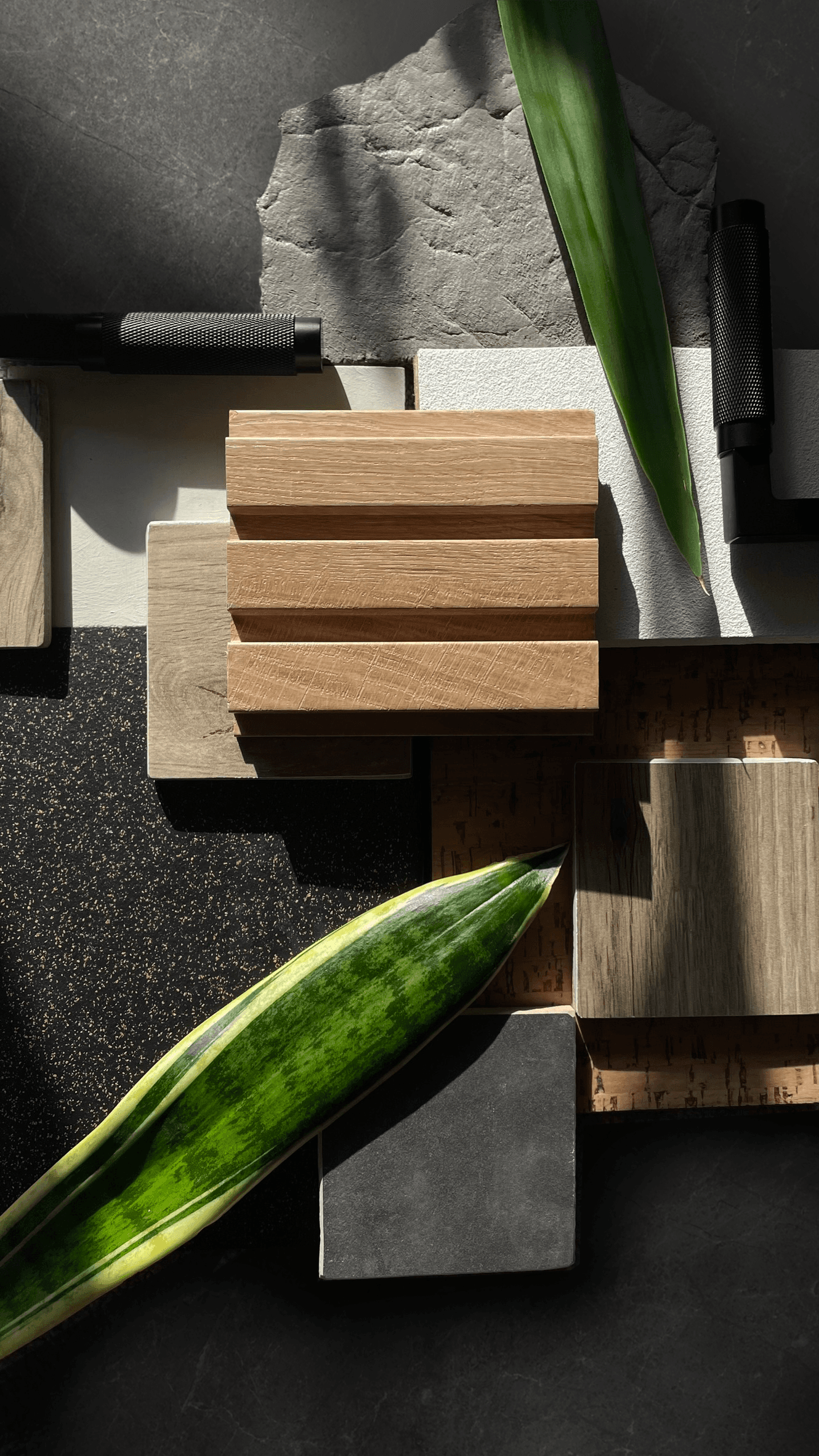 Modern interior materials palette with wood blocks, concrete, and green plant leaves