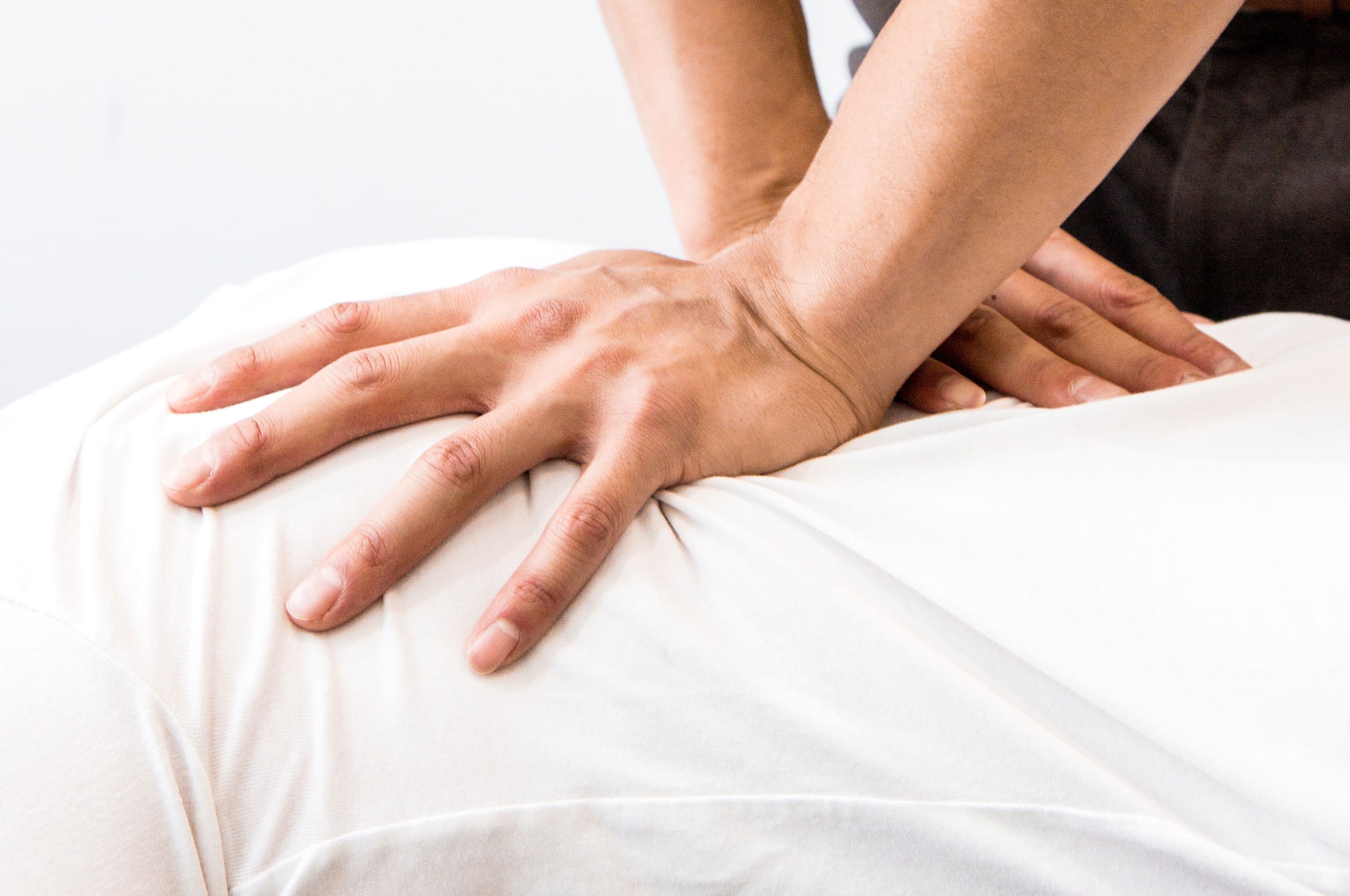 A practitioner's hands applying manual therapy to a patient's lower back.