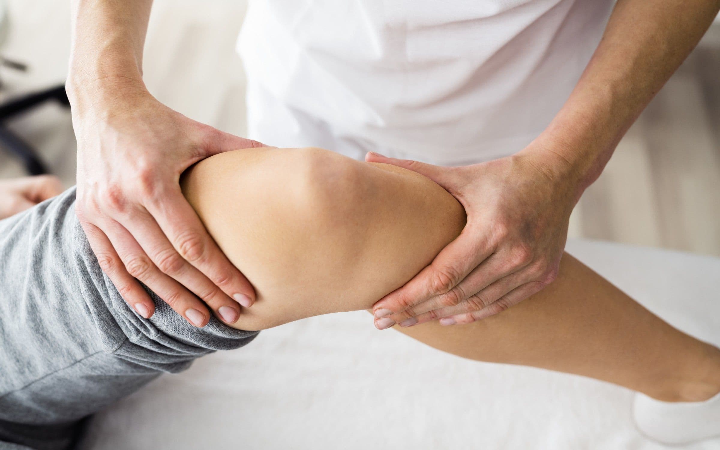 A practitioner’s hands supporting a patient’s knee during an assessment