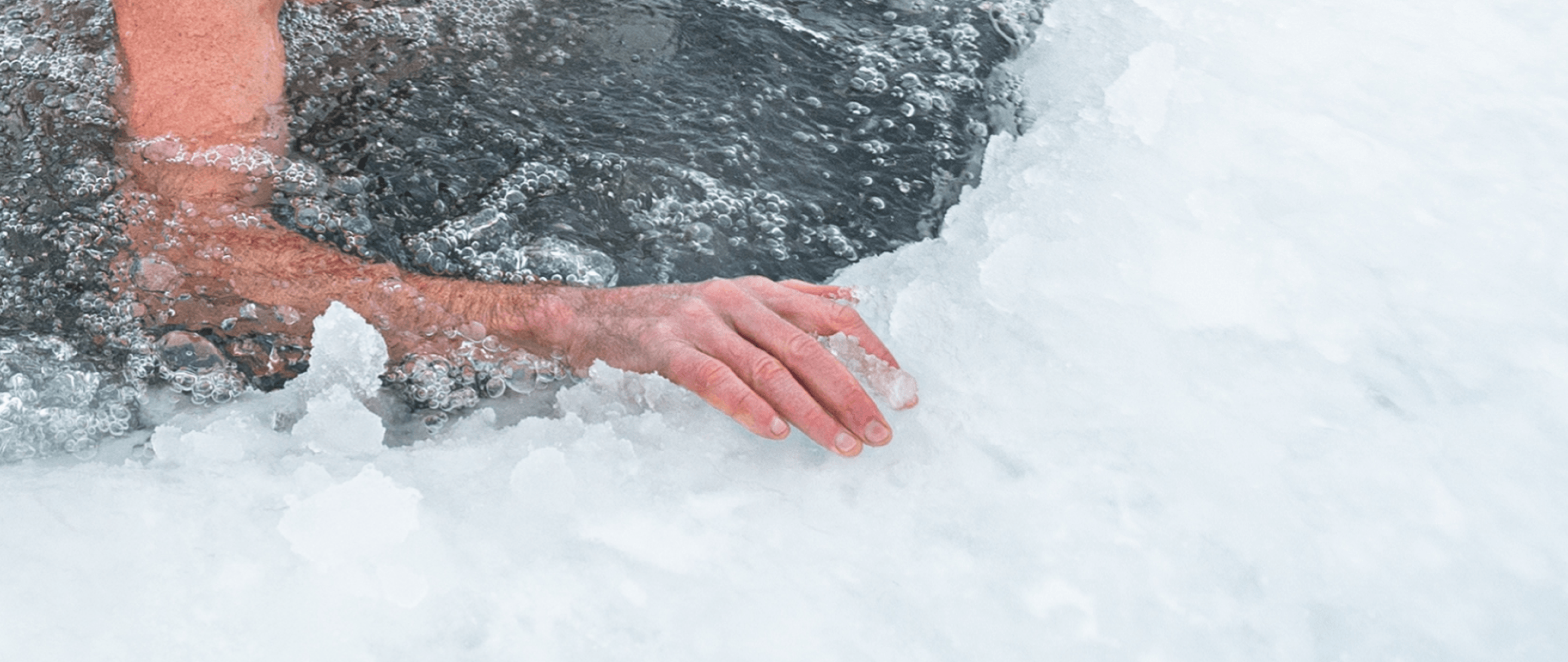 A close-up photo of a person’s hand resting on ice during an ice bath session, showing cold therapy in progress.