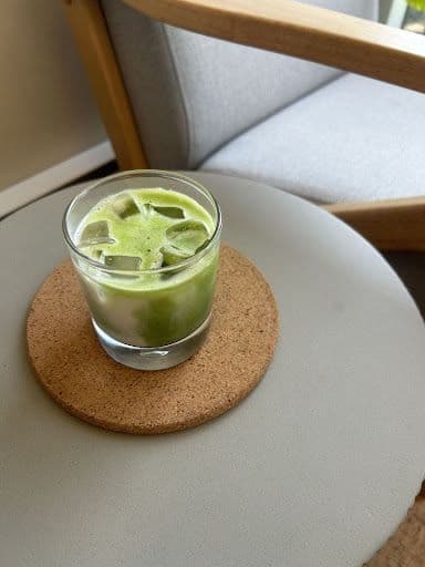 Short glass with iced matcha latte on a grey table