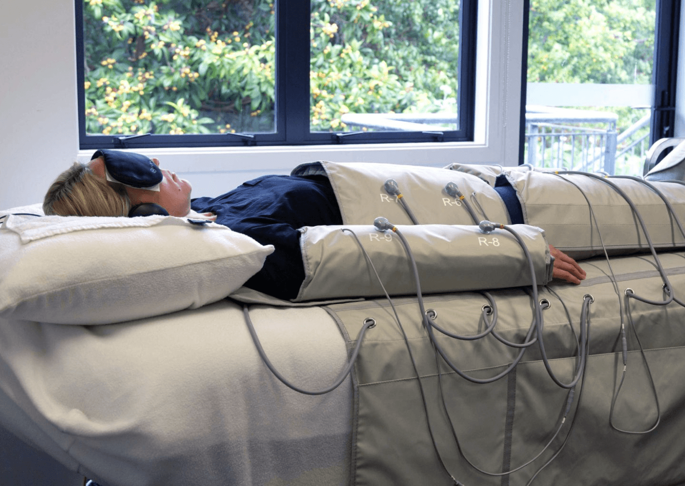 Photo of a person undergoing compression therapy, lying on a treatment bed with connected equipment.