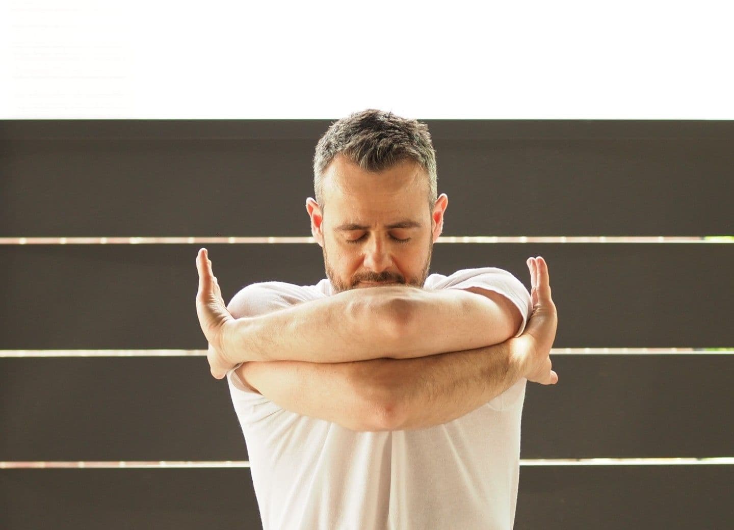Dr. David Gabriele standing with his arms crossed at his chest, eyes closed, at the end of a Tai Chi movement.